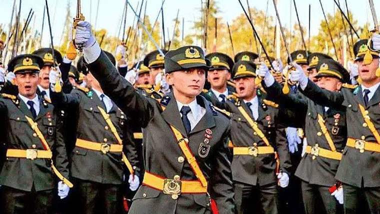 Askeri üniforma giymiş bir grup asker, ellerinde kılıçlarla havaya kaldırmış.