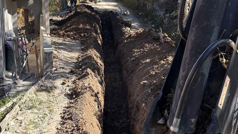 Koyulhisar'da kazılmış bir yol, yan tarafında iş makineleri ve işçiler görünüyor.