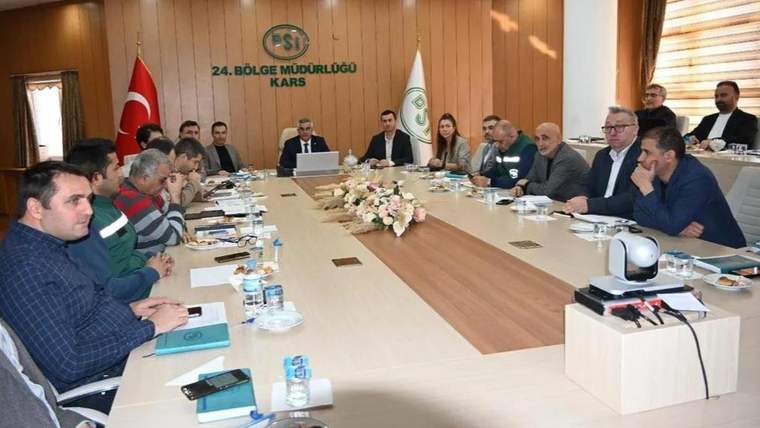 DSİ 24. Bölge Müdürlüğü Kars yazılı salonda, toplantı masası çevresinde çok sayıda kişi oturuyor.
