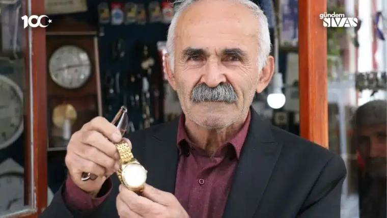 Saat tamirciliği yapan bir usta, elinde altın renkli bir saat tutuyor.