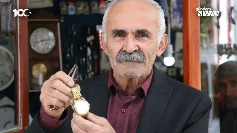Saat tamirciliği yapan bir usta, elinde altın renkli bir saat tutuyor.