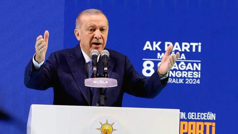 Mikrofon önünde konuşan bir kişi, elleriyle jest yapıyor.