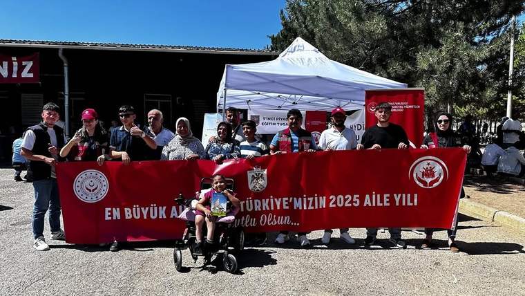 Kışlada bir grup insan, "Aile Yılı" yazılı pankartla poz veriyor.