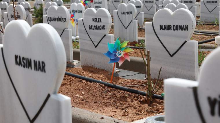 Kalp şeklinde mezar taşlarının bulunduğu bir mezarlıkta, renkli bir çiçek rüzgâr gülü yer alıyor.