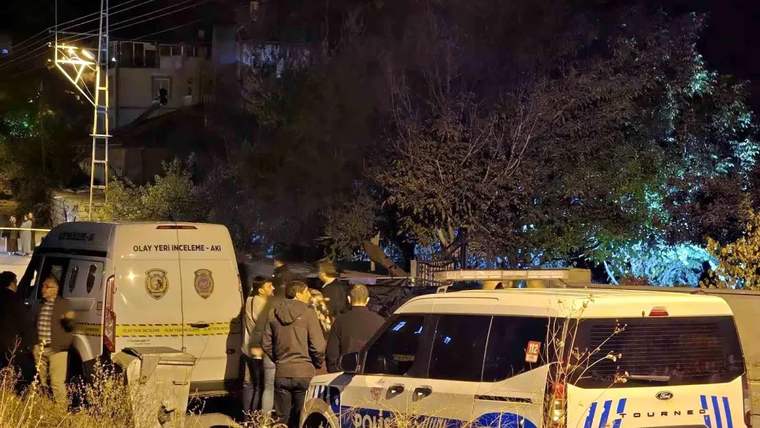 Gece aydınlatılan sokakta olay yeri inceleme ve polis araçları yanında birkaç kişi duruyor.