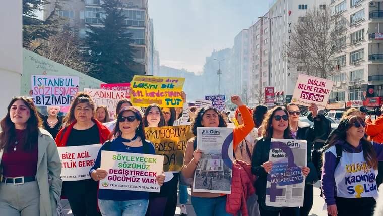 Kent sokağında yürüyen kadınlar, ellerinde çeşitli sloganların yazılı olduğu pankart ve dövizler taşıyor.