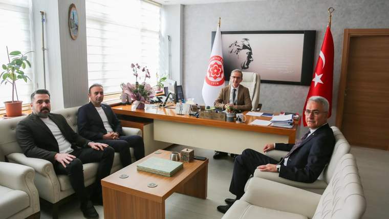 Bir masa etrafında oturan dört kişi, arka planda Türk bayrağı ve Atatürk portresi var.