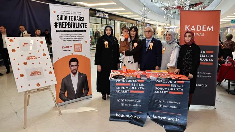 Bir grup insan, "Hep Birlikte" kampanyası için stantta poz veriyor; arka planda afiş ve broşürler var.