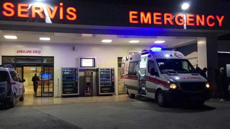 Acil servis girişinde mavi ışıkları yanan bir ambulans, kapının önünde park halinde duruyor.
