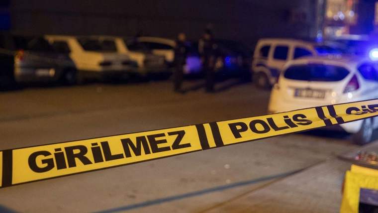 Gece karanlığında polis şeridi, park halindeki araçlar ve ışıkları açık bir polis aracı görülüyor.