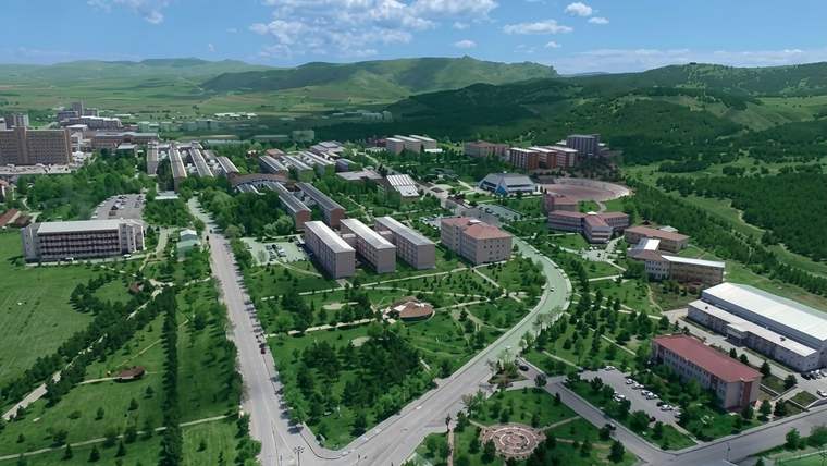 Yeşil alanlar, yollar ve çeşitli binaların bulunduğu geniş bir üniversite yerleşkesinin havadan görünümü.