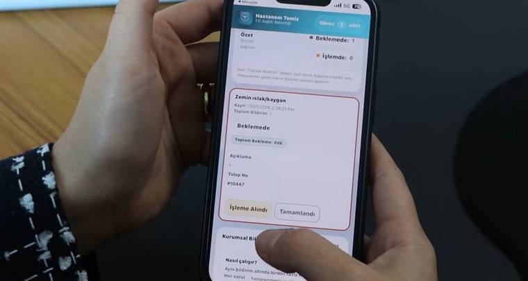 Bir kişinin tuttuğu akıllı telefonun ekranında hastane uygulamasındaki işlem bilgileri ve durum seçenekleri görülüyor.