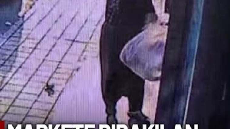 Bir kişi, marketin kapısında ekmek torbasıyla duruyor.