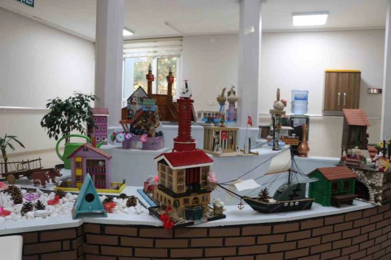 Masa üzerinde ev, gemi, kuyu ve çeşitli dekoratif el işi maketlerinin sergilendiği bir salon.