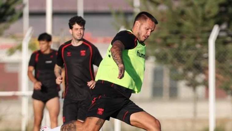 Antrenman yapan futbolcular, yeşil yelek giymiş bir oyuncunun topa vurduğu anı gösteriyor.