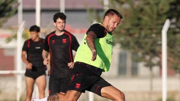 Antrenman yapan futbolcular, yeşil yelek giymiş bir oyuncunun topa vurduğu anı gösteriyor.