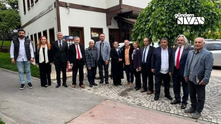 Bir grup insan, bir binanın önünde bir araya gelmiş, bazıları resmi kıyafetler giymekte.