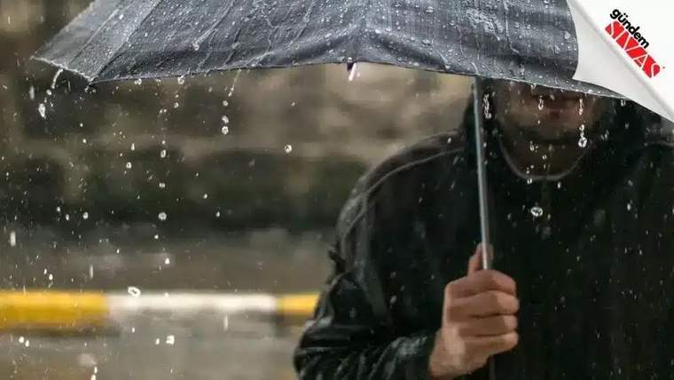 Yağmur altında bir kişi, şemsiyesini tutarak dışarıda duruyor.