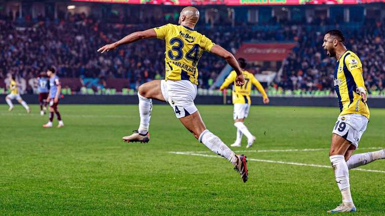 Sarı-lacivertli forma giymiş bir futbolcu, sevinçle havaya zıplıyor.