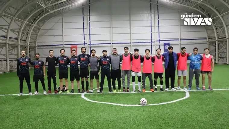 Futbol sahasında, farklı kıyafetler giymiş iki takım oyuncuları yan yana duruyor.