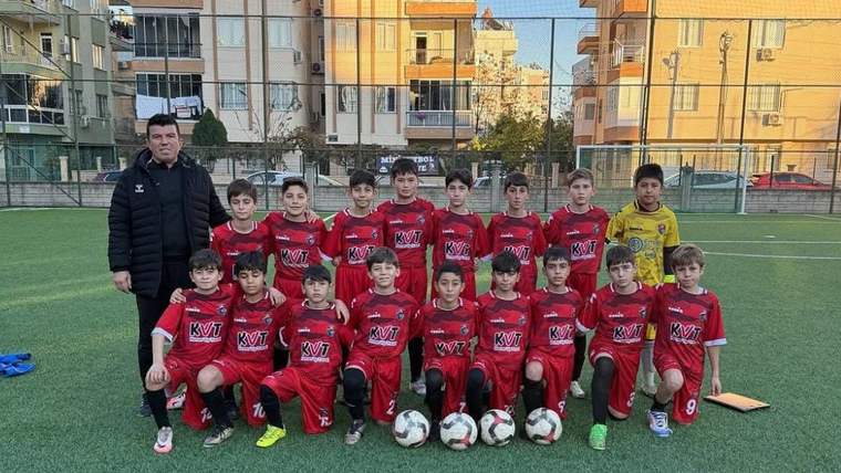Kemer Belediye U12 futbol takımı, antrenörleriyle birlikte poz veriyor.
