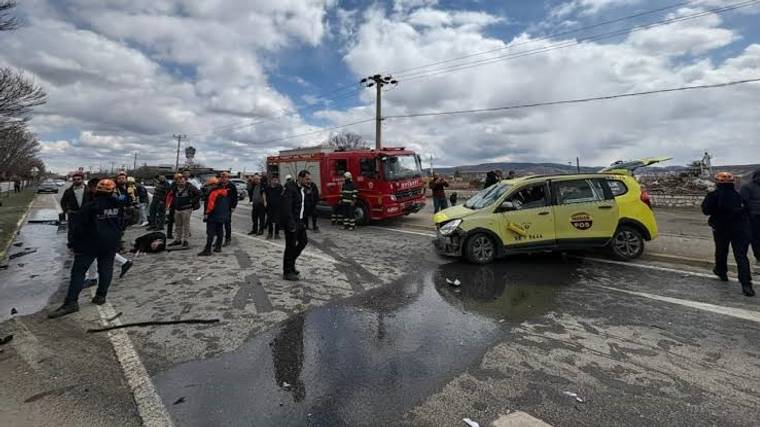 Yağışlı bir alanda kırmızı itfaiye aracı, sarı ambulans ve çevresinde duran insanlar görülüyor.