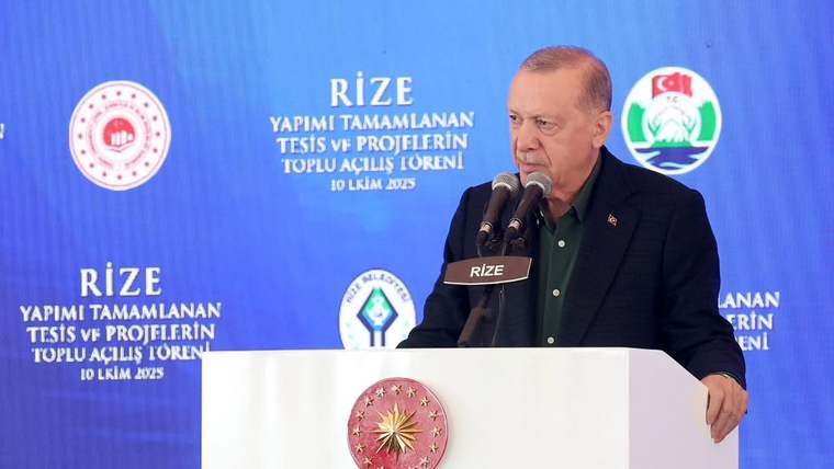 Kürsüde konuşan bir kişi, arkasında Rize yazılı mavi panonun önünde duruyor.