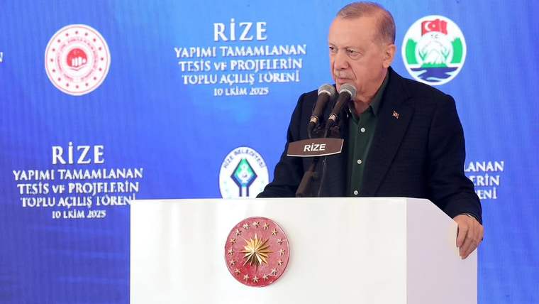 Kürsüde konuşan bir kişi, arkasında Rize yazılı mavi panonun önünde duruyor.