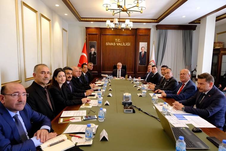 “T.C. Sivas Valiliği” yazılı salonda, uzun masa çevresinde çok sayıda kişinin katıldığı toplantı