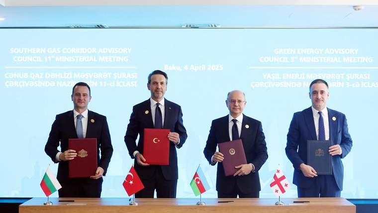Masada dört erkek, ellerinde belgelerle duruyor; önlerinde Türkiye, Azerbaycan, Bulgaristan ve Gürcistan bayrakları bulunuyor.