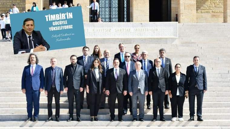 Bir grup insan, anıtta poz veriyor; arka planda büyük bir yapı yer alıyor.