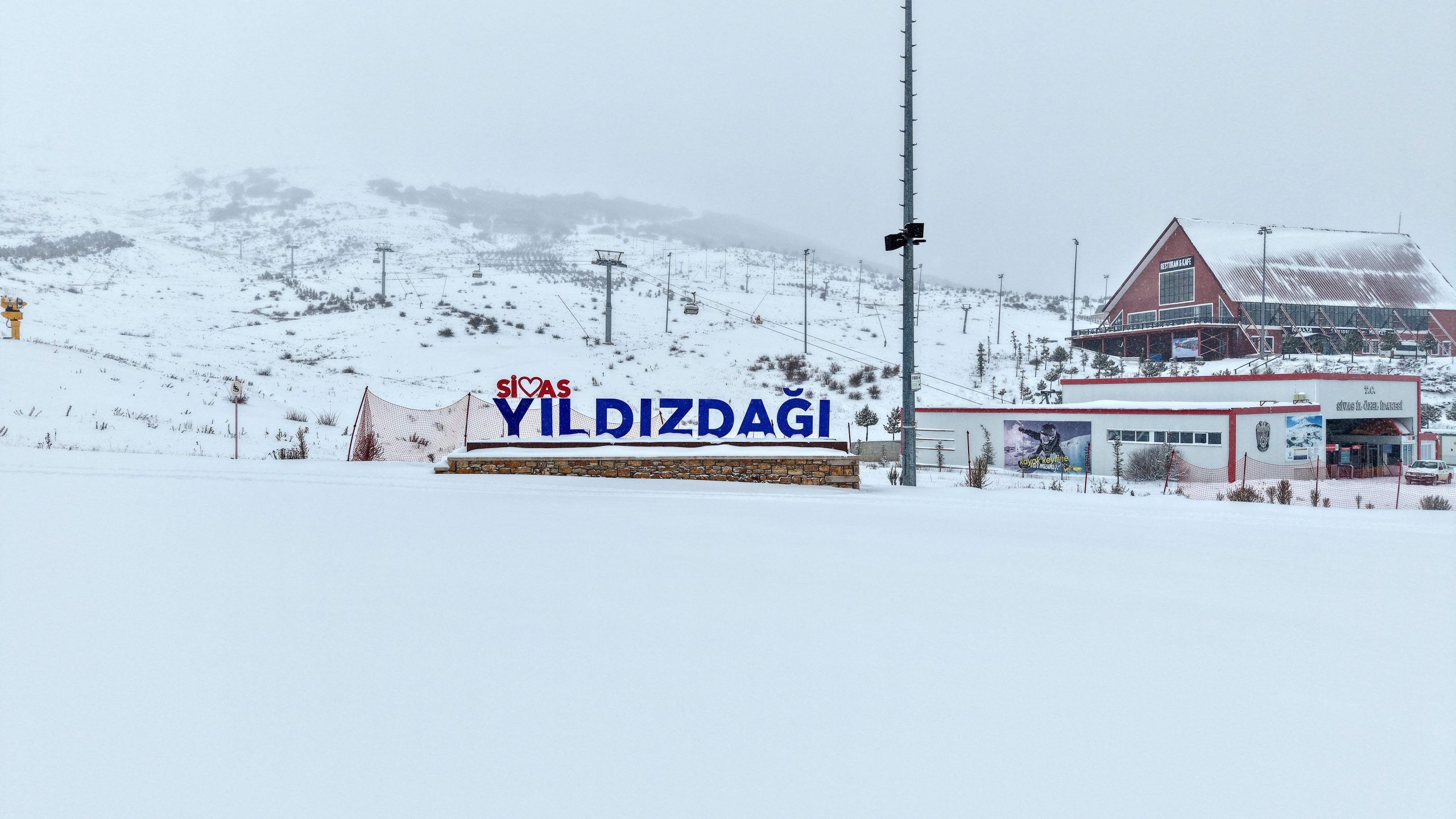 Yıldız Dağı yazılı tabela, karla kaplı alanda görünmekte, arka planda da dağlar yer almakta.