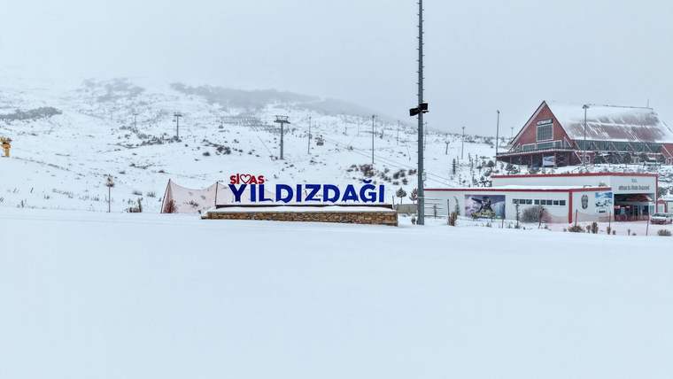 Yıldız Dağı yazılı tabela, karla kaplı alanda görünmekte, arka planda da dağlar yer almakta.