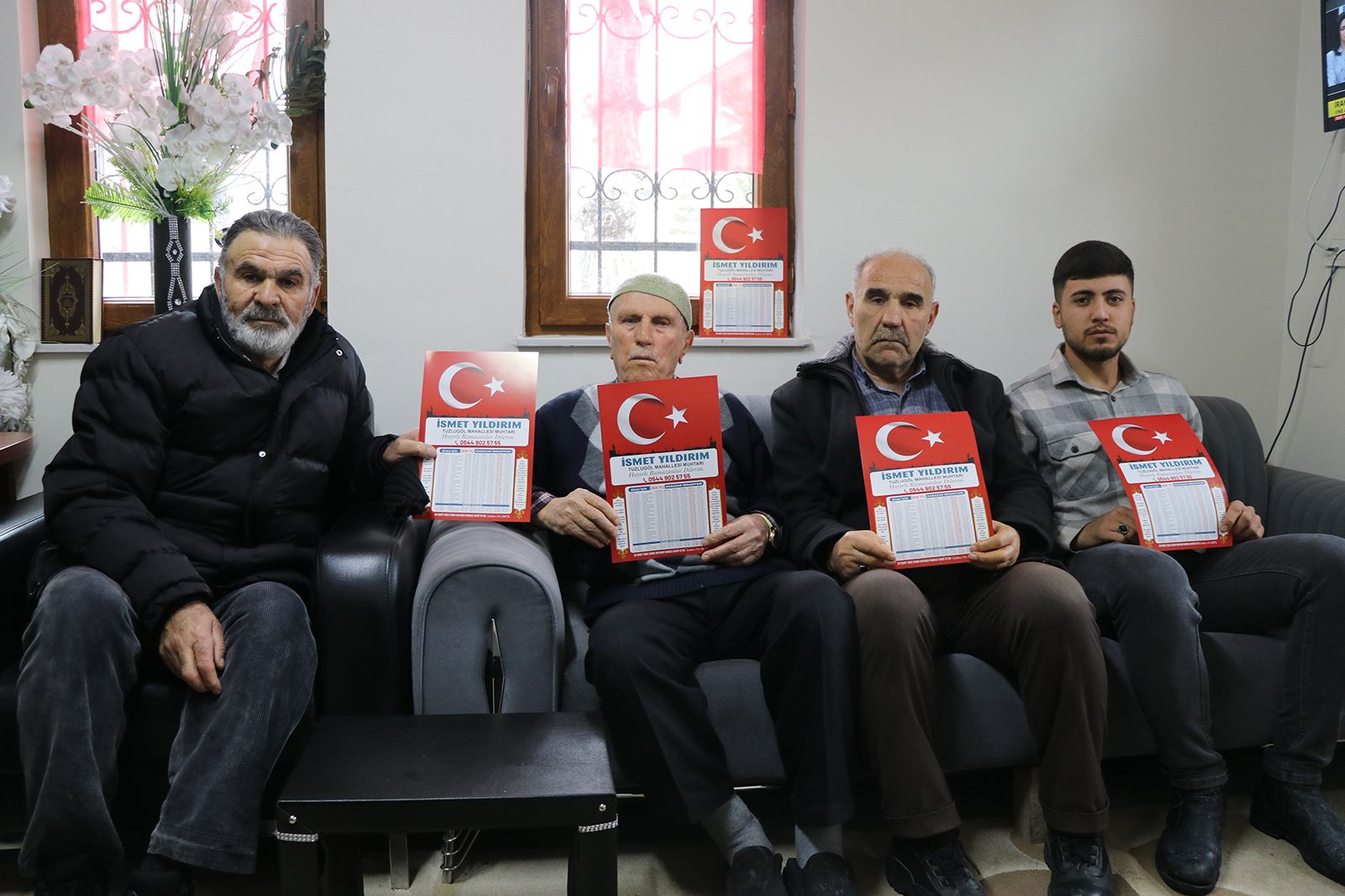Dört kişi, Türk bayrağı simgeli imsakiye tutarak bir koltukta oturuyor.