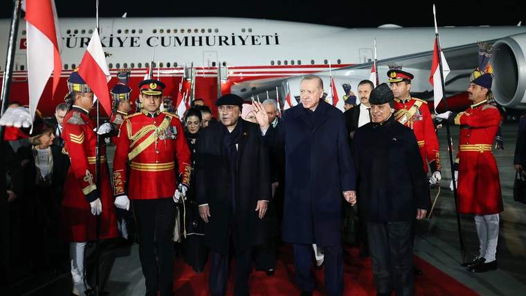 Cumhurbaşkanı Erdoğan, Pakistan'da resmi bir karşılama töreninde, el ele tutuşarak yürürken görülüyor.