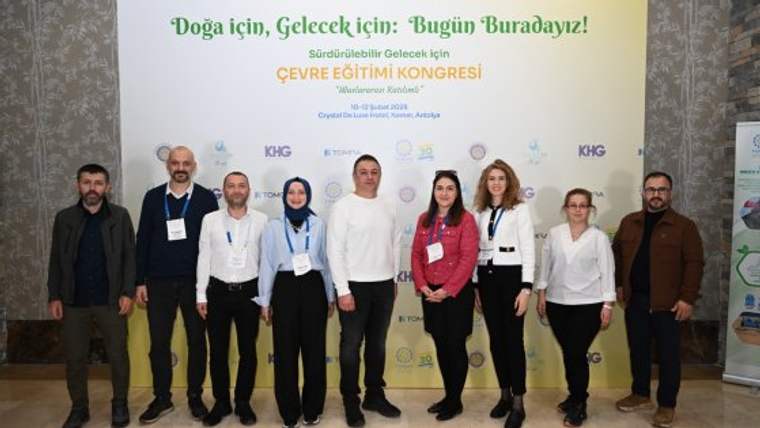 Çevre Eğitimi Kongresi'nde bir grup insan, arka planda kongre afişi ile birlikte poz veriyor.