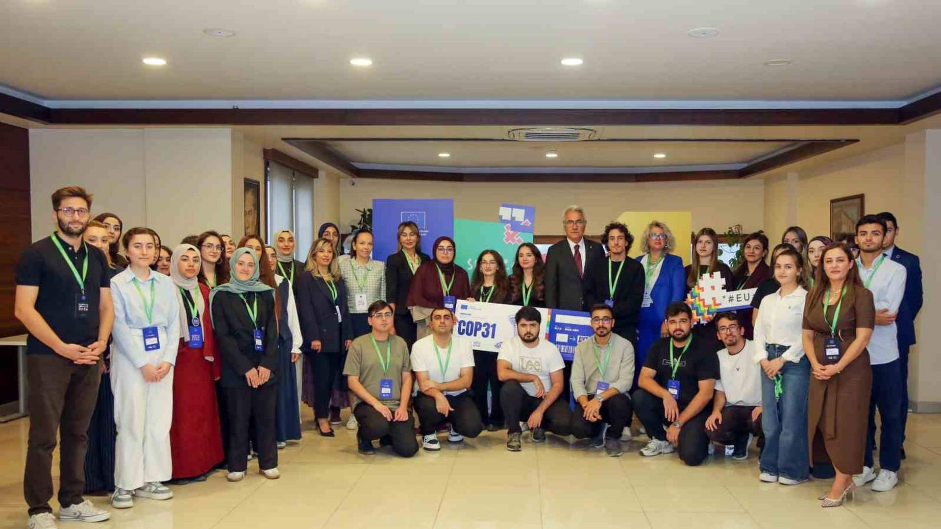 Toplantı salonunda, arkalarında COP31 yazılı afişler bulunan kalabalık bir grup birlikte poz veriyor.