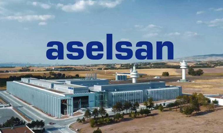 Geniş bir tesis yerleşkesinin üzerinde büyük “aselsan” yazısı, arka planda tarım arazileri ve kuleler görülüyor.