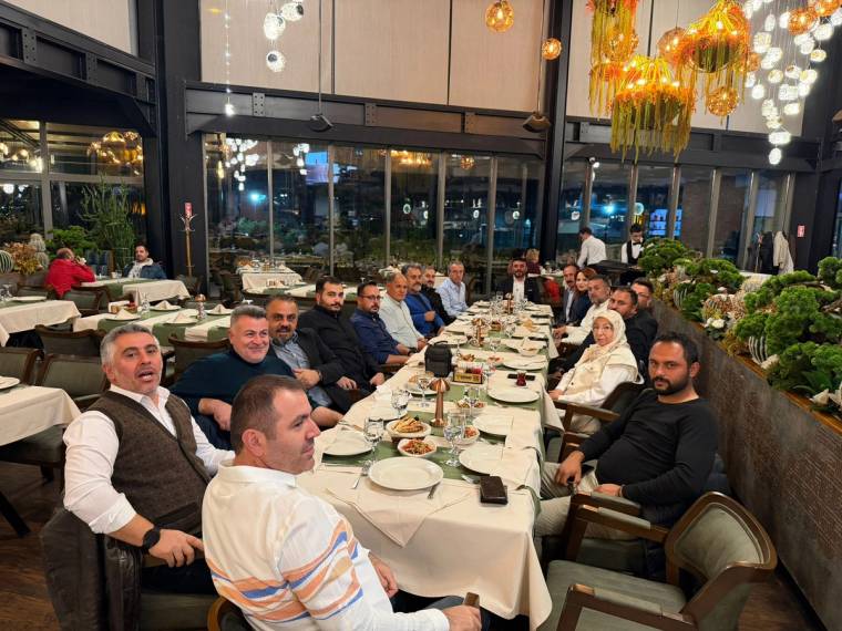 Bir restoranda oturan kalabalık bir grup, masada yemek ve içecekler var.