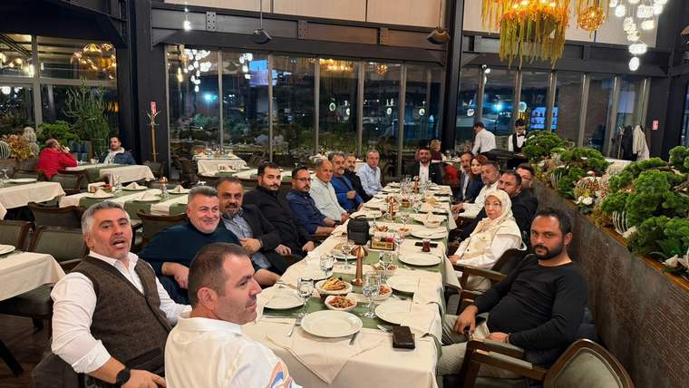 Bir restoranda oturan kalabalık bir grup, masada yemek ve içecekler var.