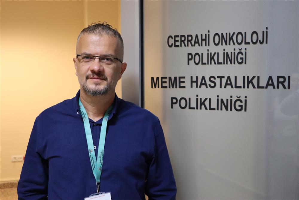 Bir kişi, “Cerrahi Onkoloji Polikliniği” ve “Meme Hastalıkları Polikliniği” yazılı kapı önünde duruyor.