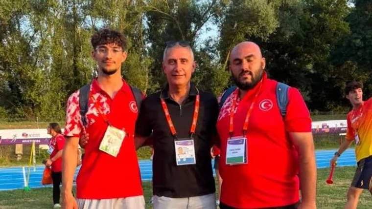 Kırmızı tişört giymiş üç kişi, bir atletizm pistinin yanında poz veriyor.