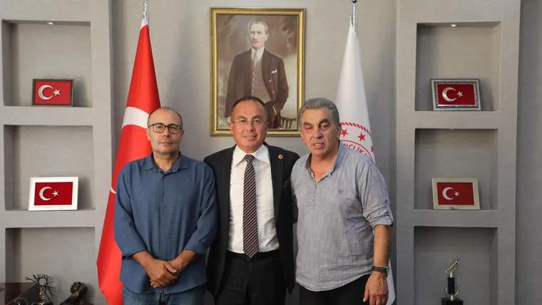 Sivas Gençlik ve Spor İl Müdürlüğü'nde üç kişi, masanın önünde poz veriyor.