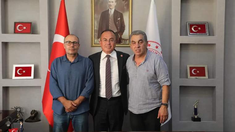 Sivas Gençlik ve Spor İl Müdürlüğü'nde üç kişi, masanın önünde poz veriyor.