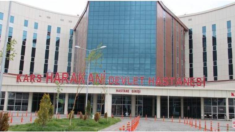 Cam cepheli Kars Harakani Devlet Hastanesi binasının ön cephesinde “HASTANE GİRİŞİ” yazısı görülüyor.