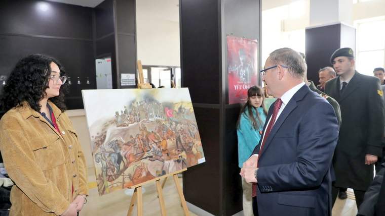 Vali Ziya Polat, bir sanatçıyla birlikte "Çanakkale" temalı resim sergisinin açılışında bir tabloya bakıyor.