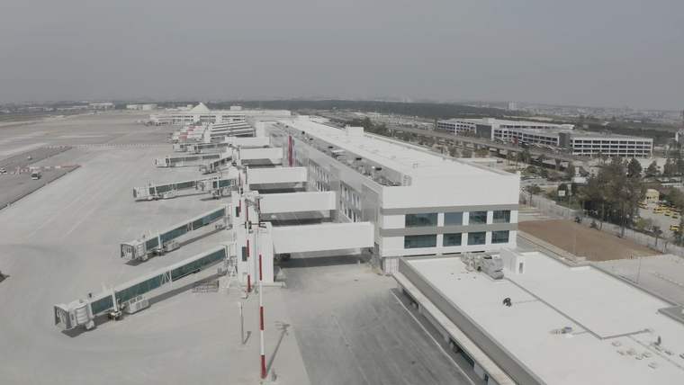 Havalimanı terminal binası boyunca sıralanan yolcu köprüleri ve geniş apron alanı havadan görülüyor.