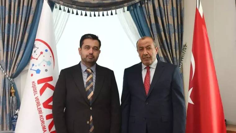 KVKK Başkanı Faruk Bilir ve yanında bir kişi, arka planda Türk bayrağı ve KVKK bayrağı ile birlikte duruyorlar.