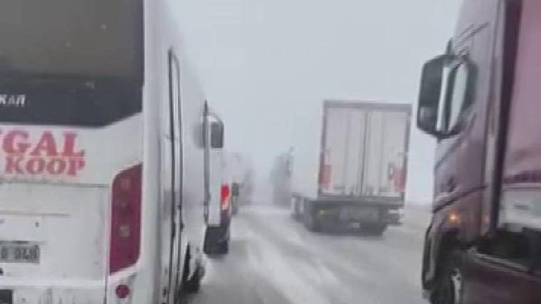 Karla kaplı yolda yan yana dizilmiş araçlar, yoğun kar nedeniyle ilerlemekte zorlanıyor.