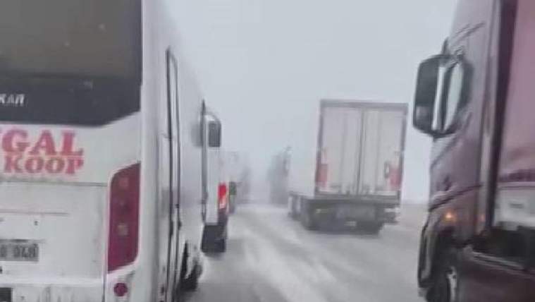 Karla kaplı yolda yan yana dizilmiş araçlar, yoğun kar nedeniyle ilerlemekte zorlanıyor.